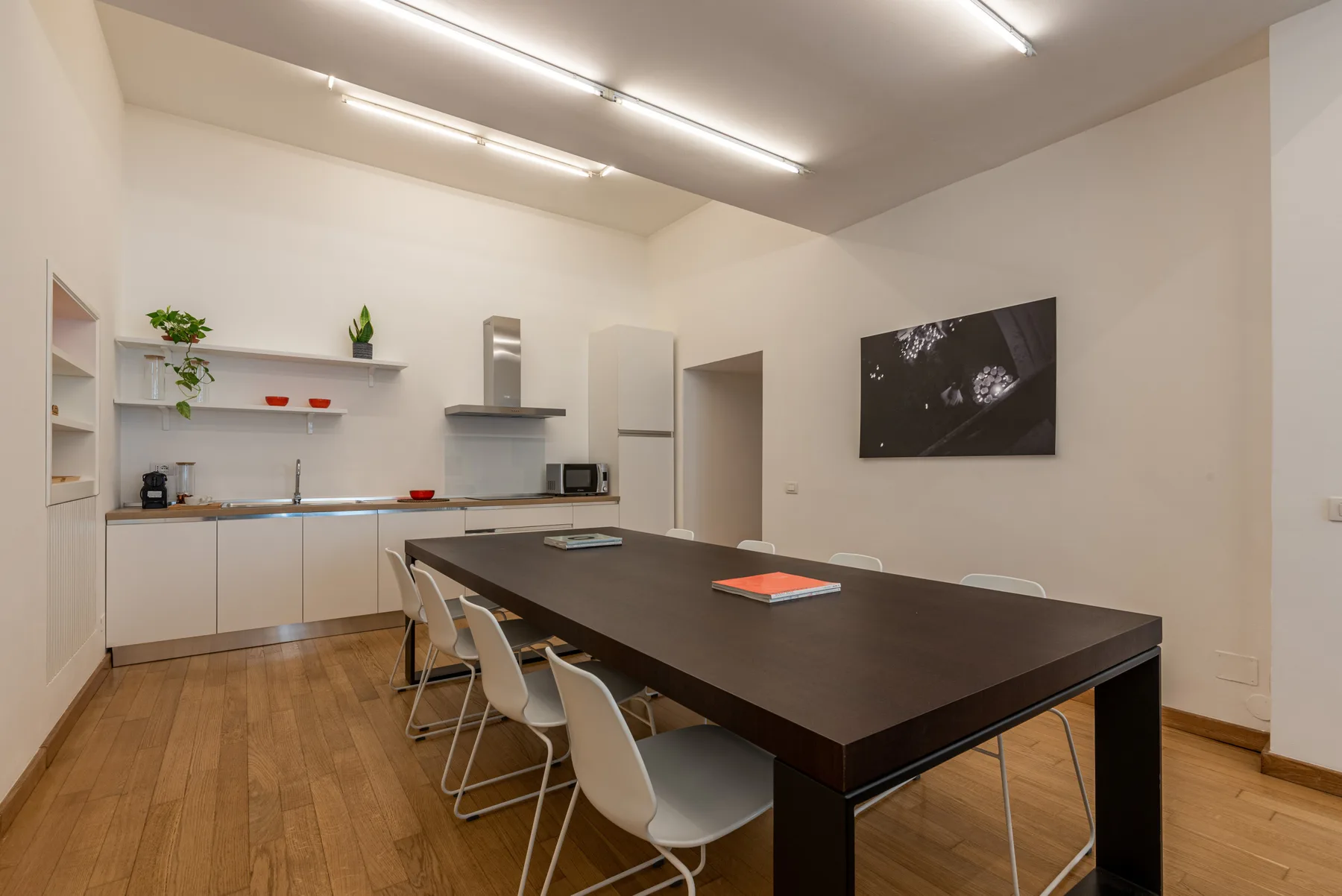 Comedor con una mesa larga y sillas junto a una cocina compacta.
