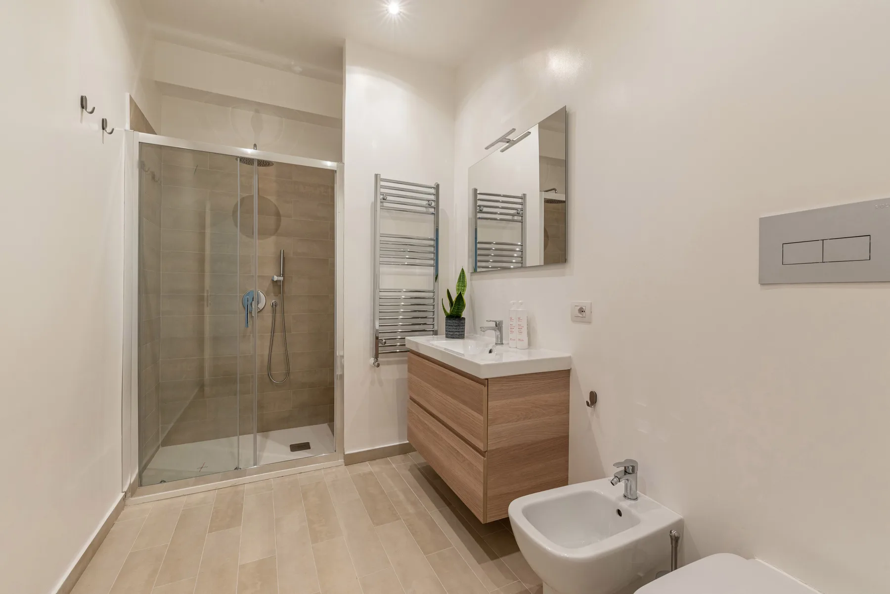Un baño luminoso con ducha de vidrio, lavabo y bidé.