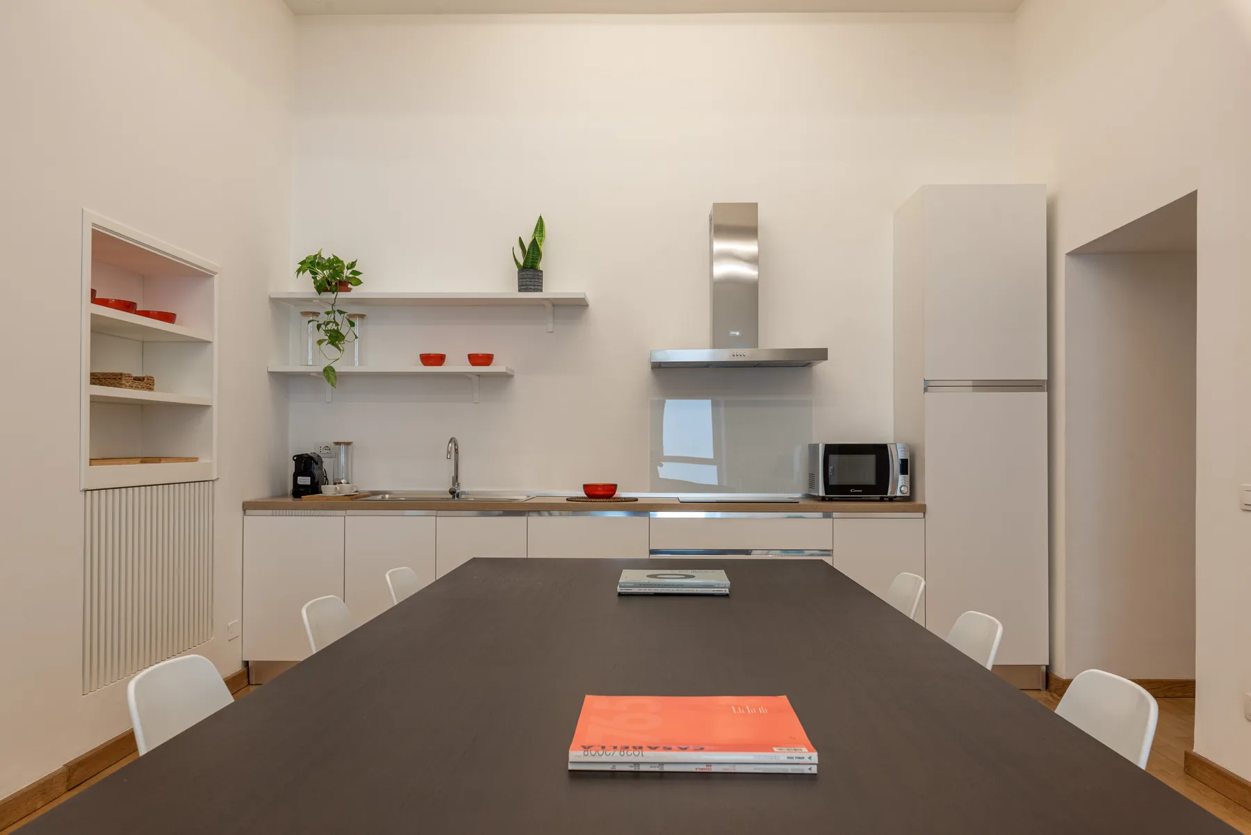 Una mesa de comedor da a una cocina luminosa con armarios y encimera.
