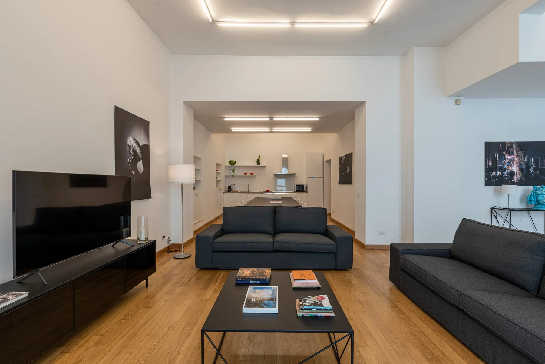 Una sala de estar moderna con asientos oscuros, un televisor y una mesa de centro.