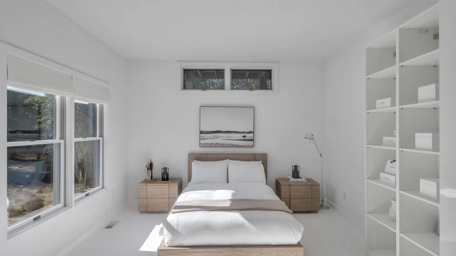A bright bedroom with a neatly made bed and built-in shelving.