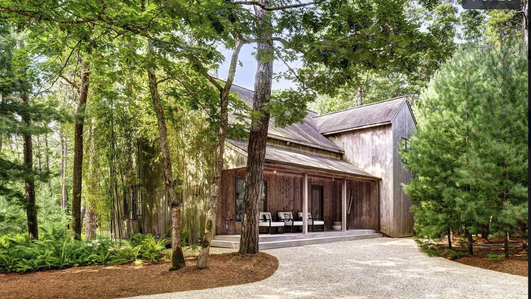 A wooded cabin exterior with a covered porch and a paved driveway.