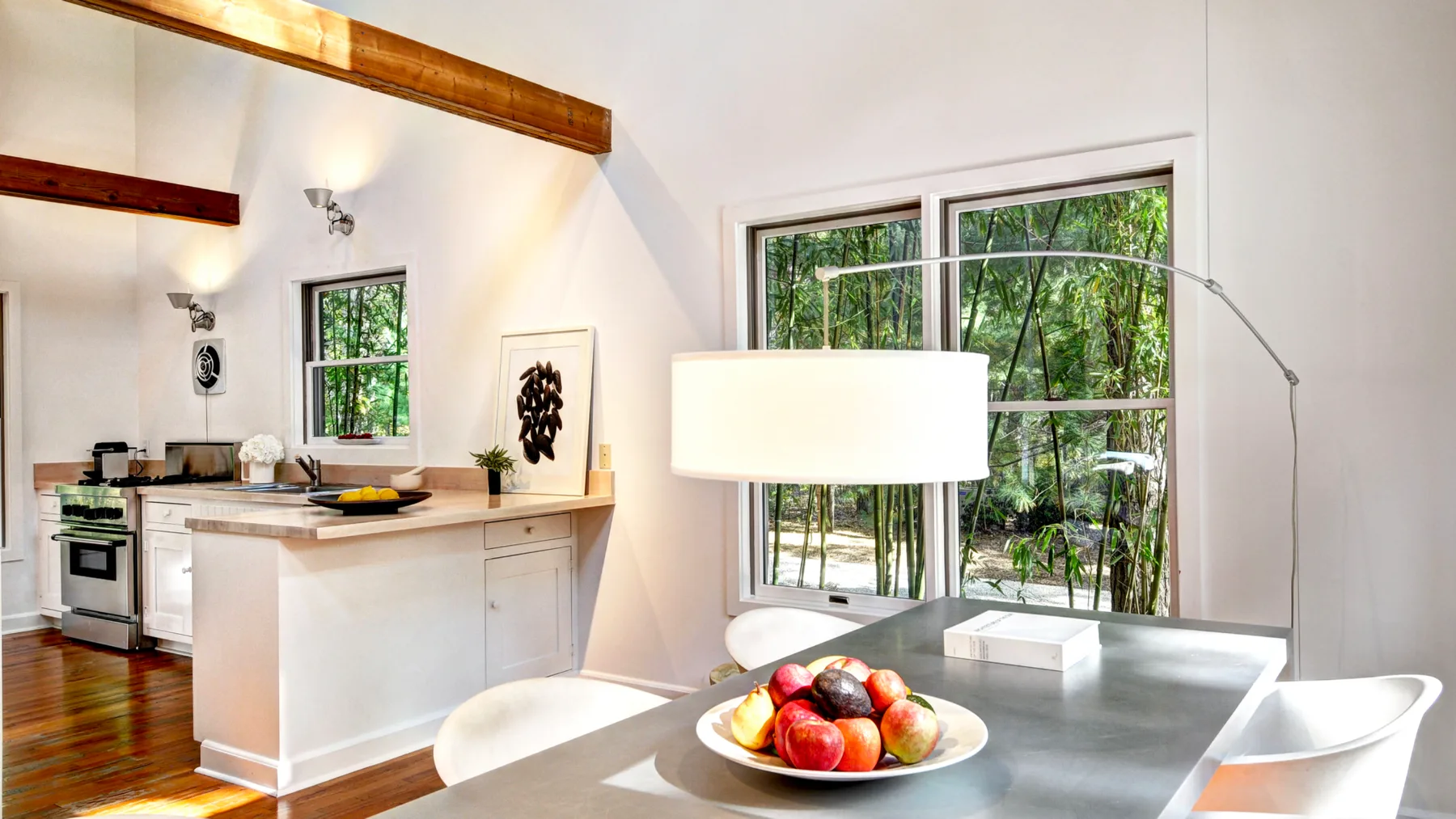 A bright kitchen and dining area with a table beside large windows.
