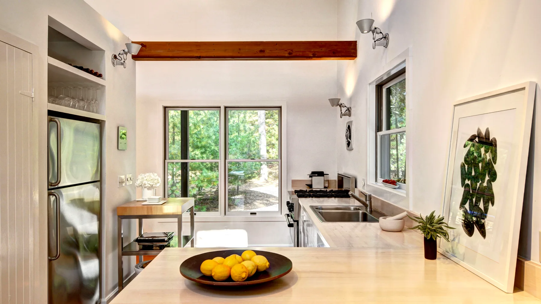 A bright kitchen with a central island and large windows overlooking greenery.