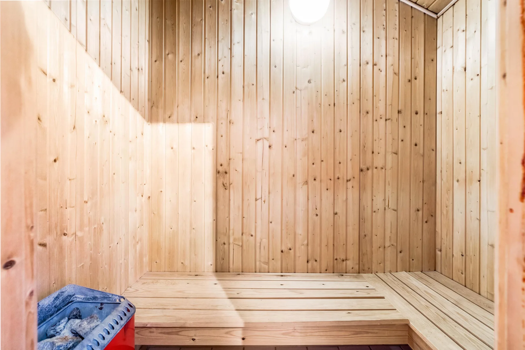 Una sauna de madera con asientos escalonados y una luz brillante en el techo.