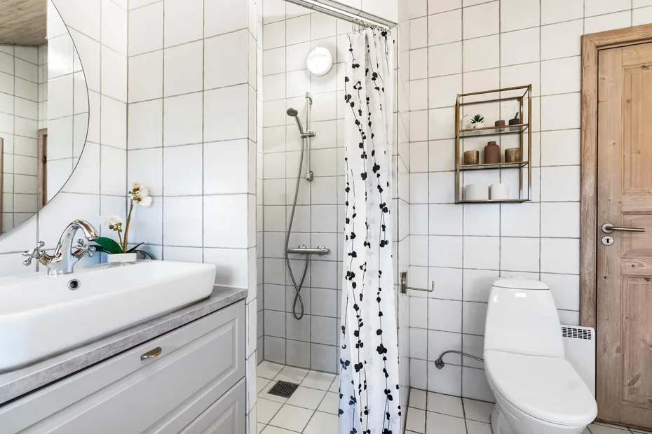 Un baño con azulejos, lavabo, ducha e inodoro.