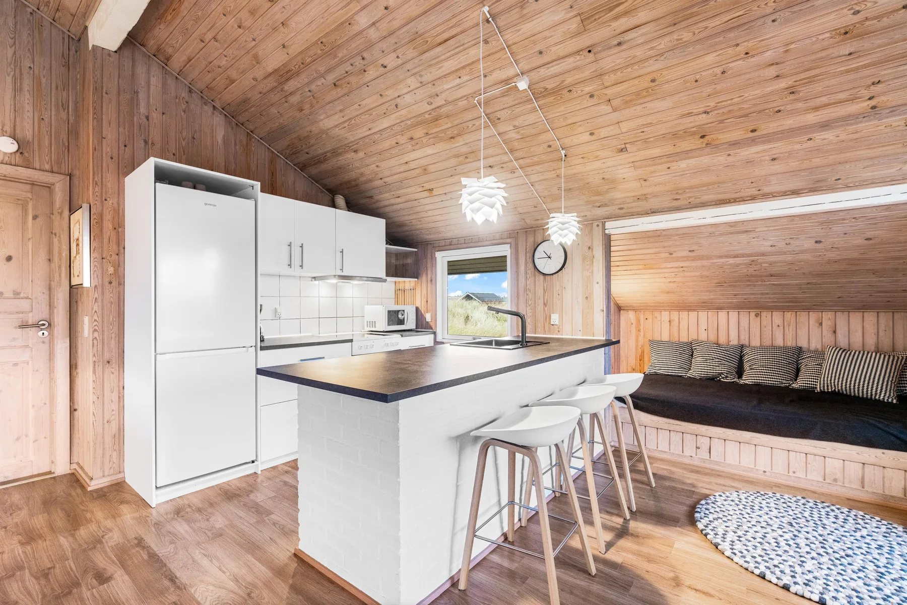 Una cocina y comedor luminosos con una isla blanca y un banco integrado.