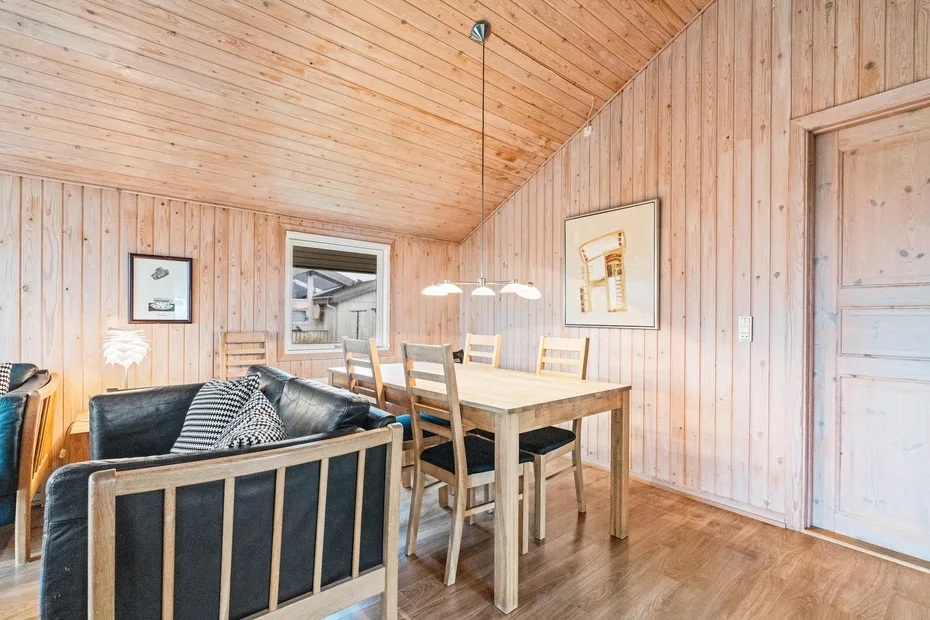 Un comedor y zona de estar revestidos de madera, con mesa y asientos.