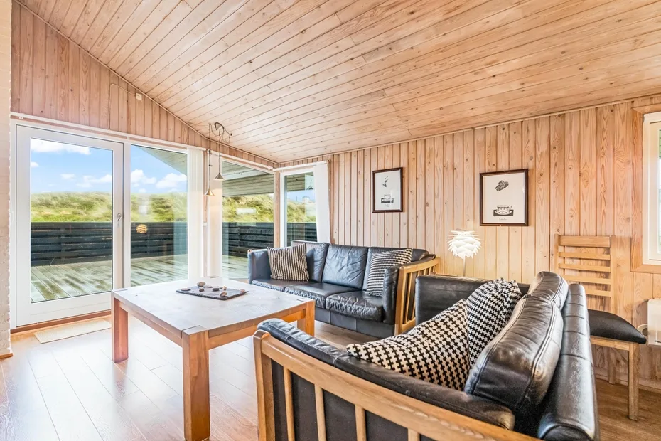 Una sala revestida de madera con asientos y ventanas grandes.