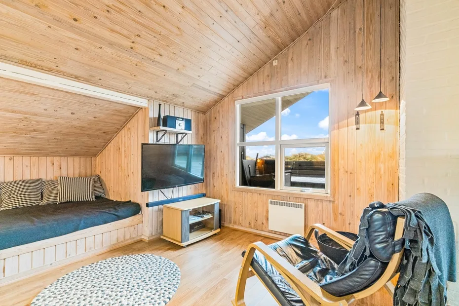 Una habitación revestida de madera con cama empotrada, televisor y ventana.