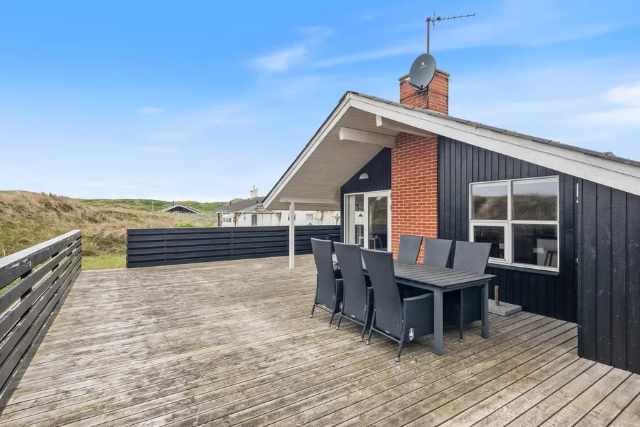 Una amplia terraza exterior con mesa de comedor y asientos junto a una casa moderna.