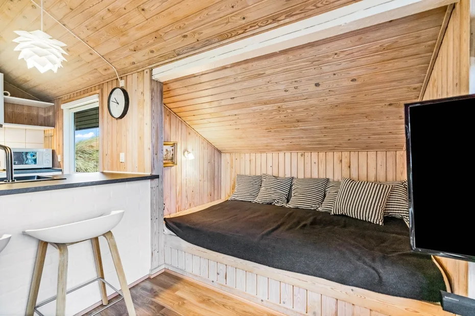 Una habitación revestida de madera con una zona elevada para sentarse y una pequeña barra de cocina.