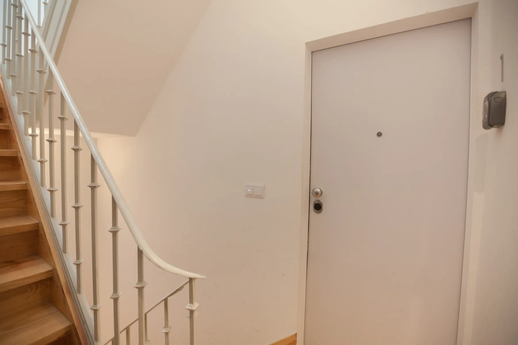 An apartment entryway with a front door beside a staircase.