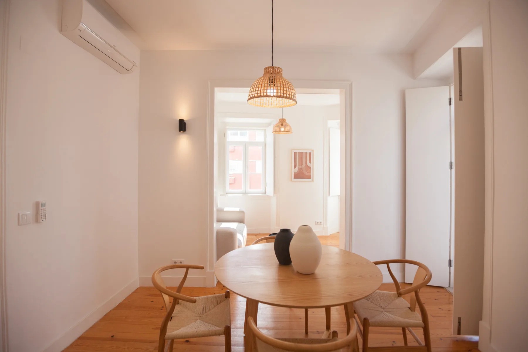 A dining area with a round wooden table and woven pendant light.