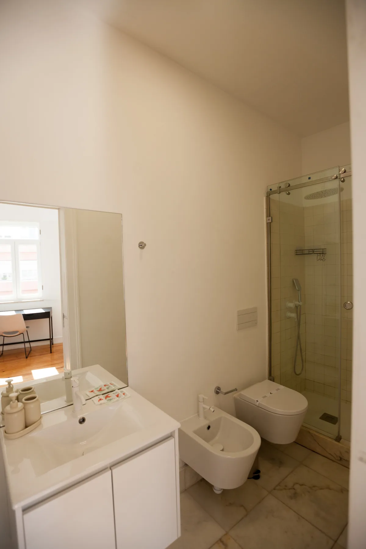A bathroom with a vanity, bidet, toilet, and glass shower.