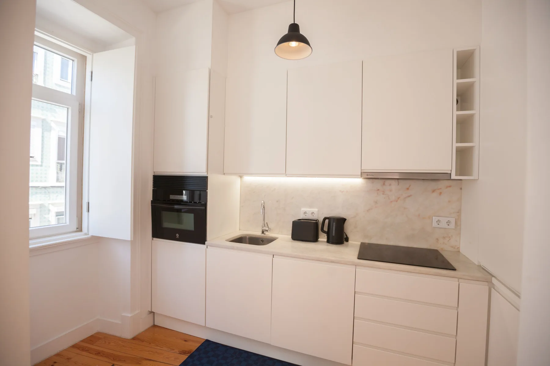 A bright kitchen with white cabinetry, a countertop, and a window.