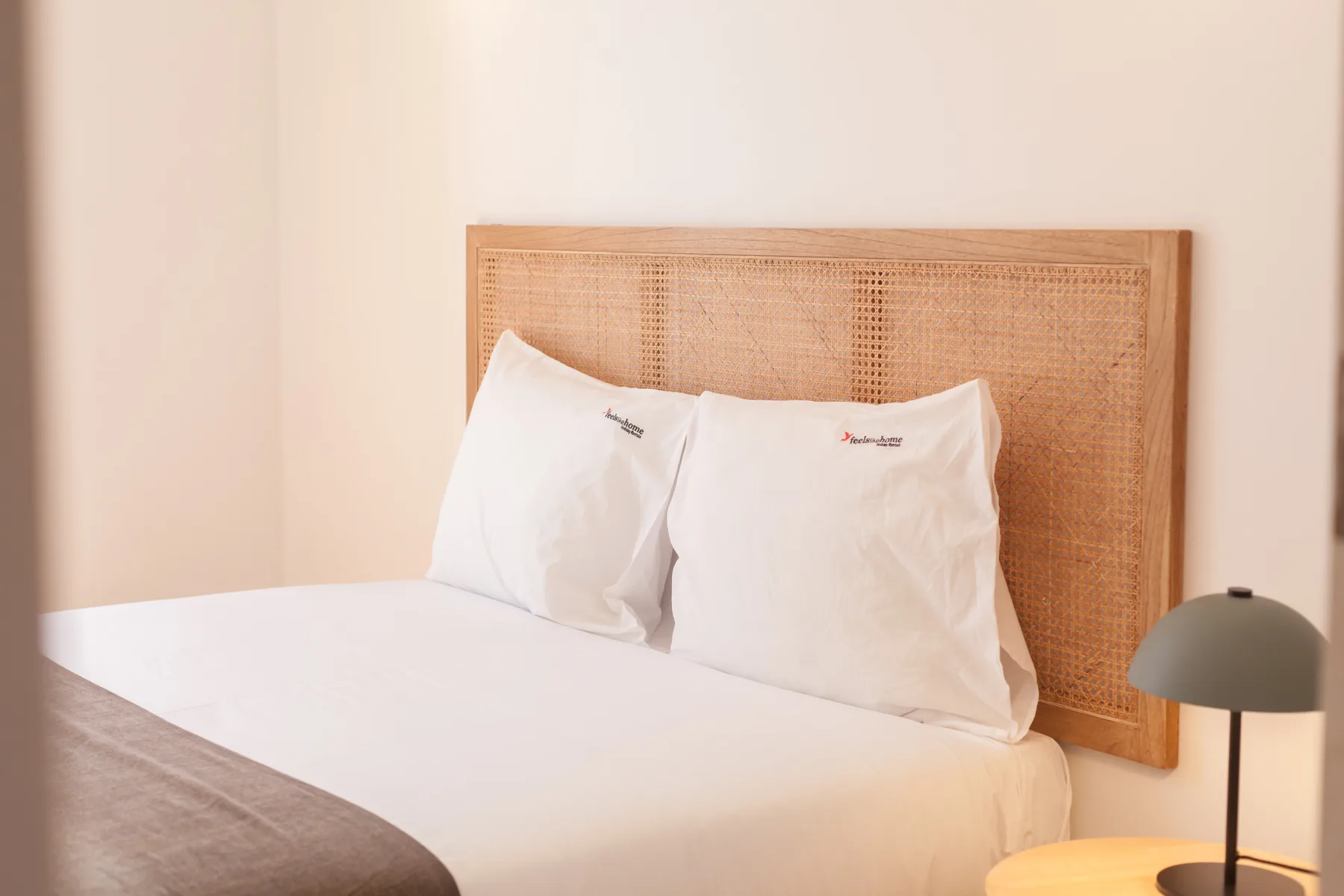 Un dormitorio con ropa de cama blanca y un cabecero tejido.