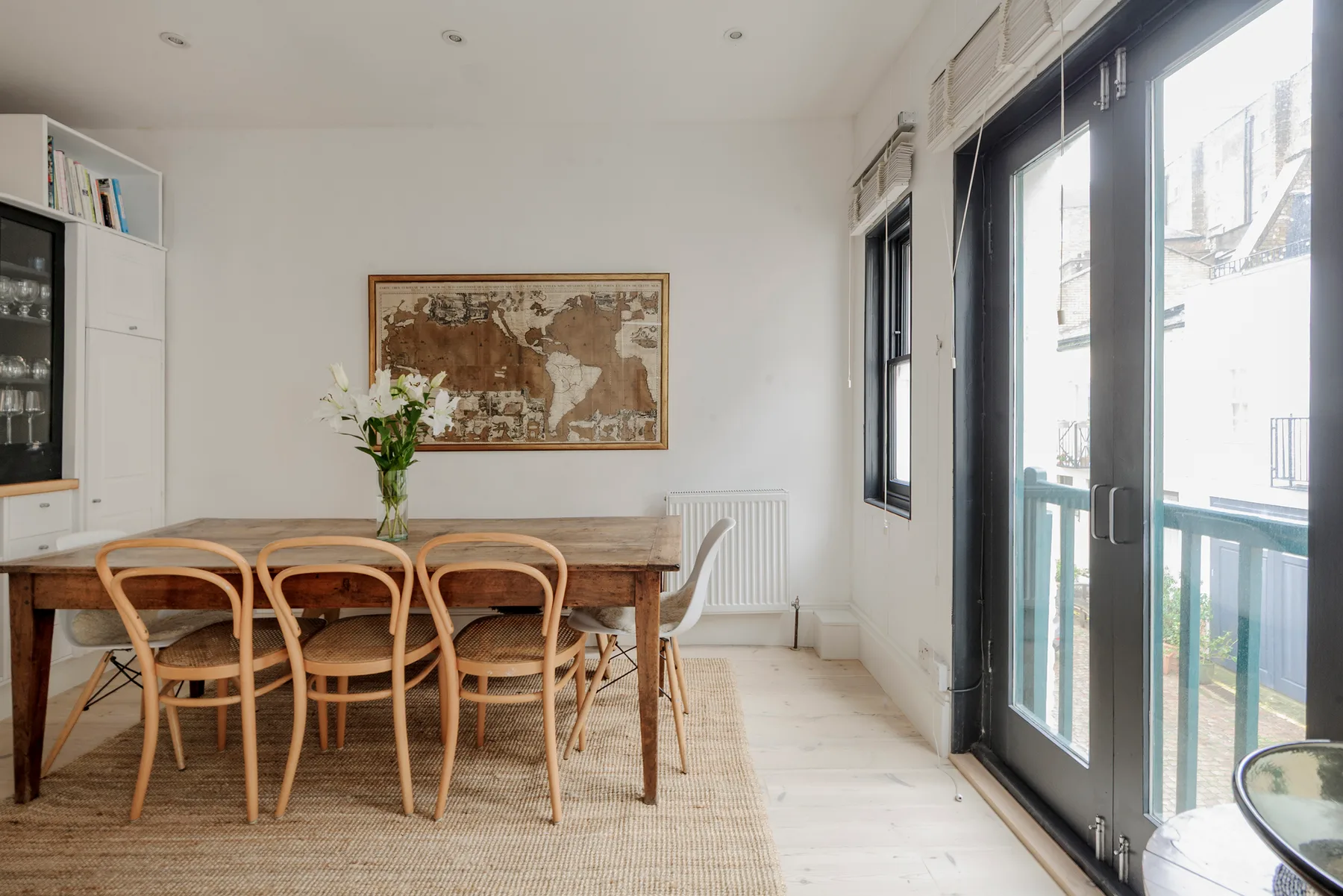 A dining area with a wooden table, chairs, and large glass doors.