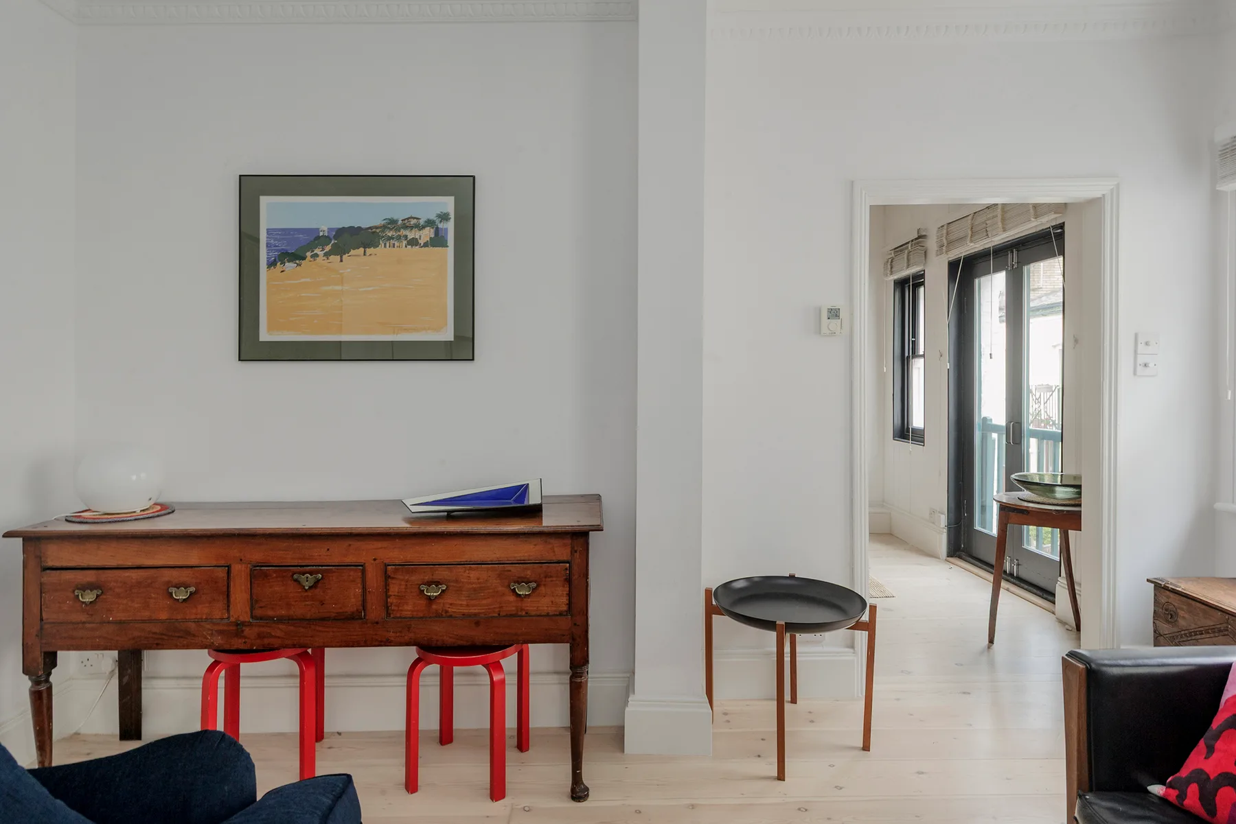 A bright living room with a wooden console beneath a framed landscape painting.