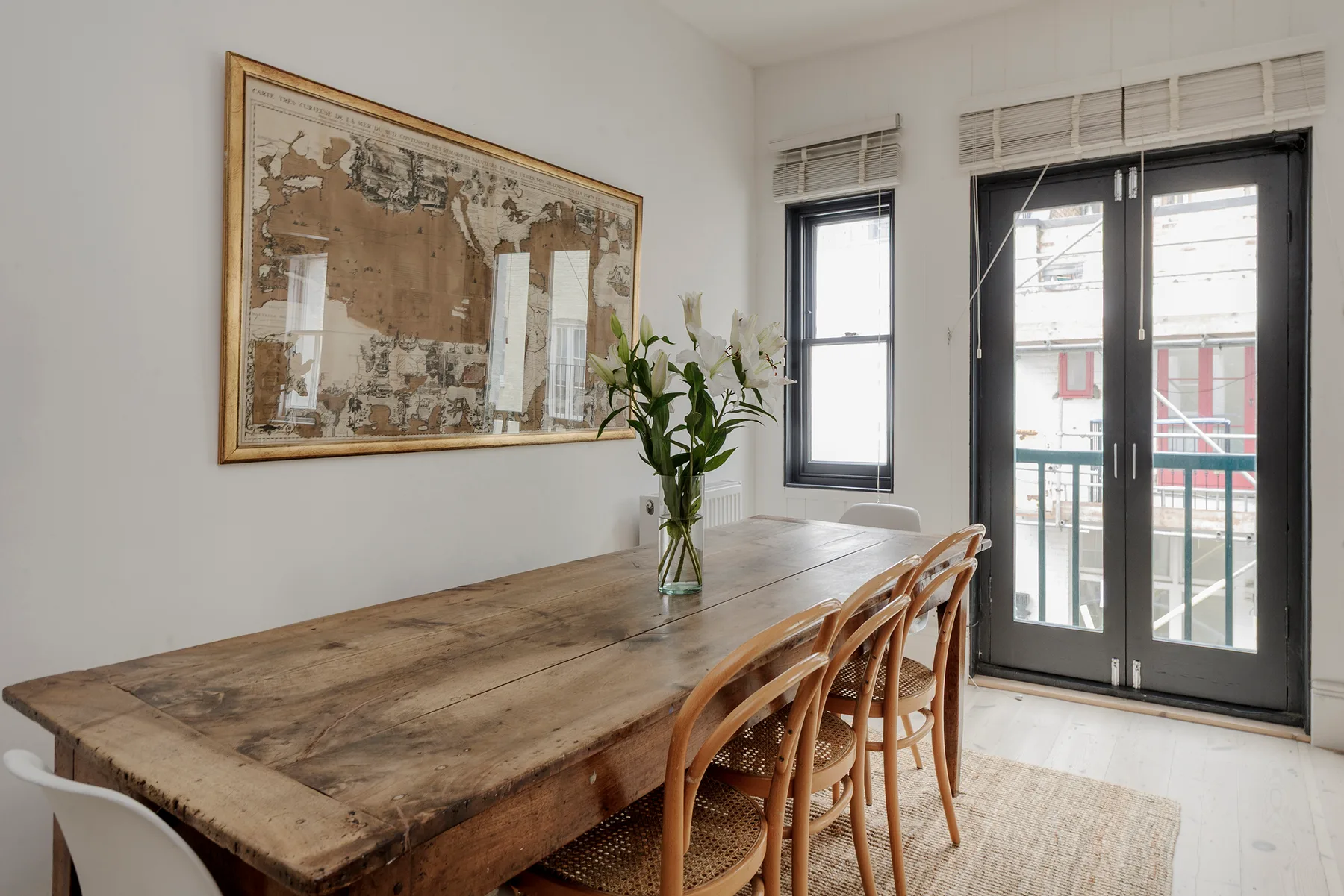 A dining area with a long wooden table and chairs beside glass doors.
