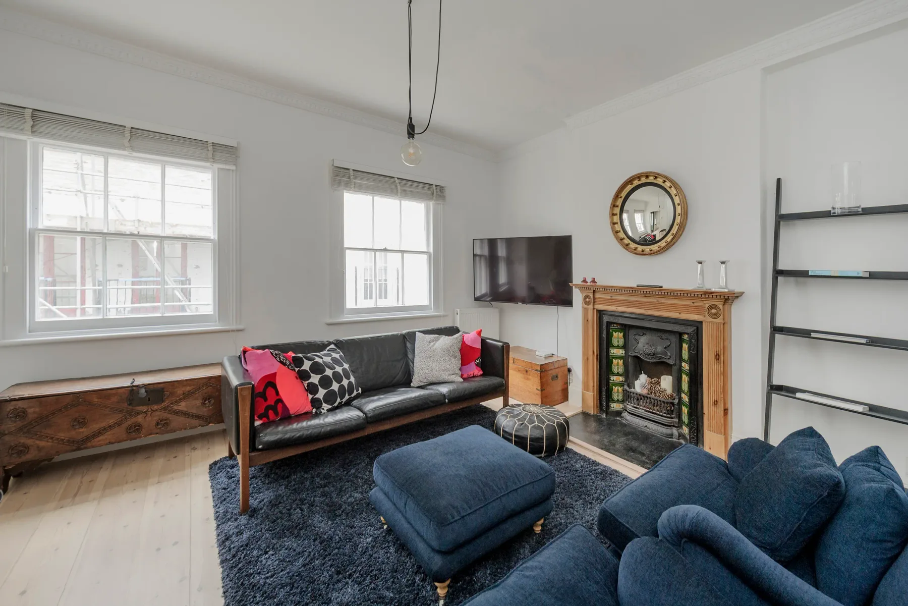 A bright living room with seating arranged around a fireplace and television.