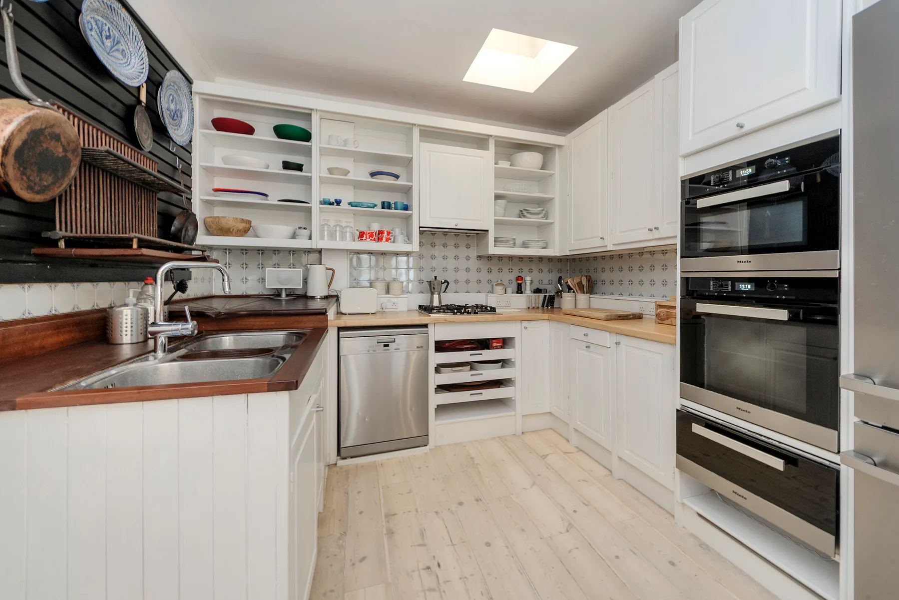 A bright kitchen with white cabinets, wooden countertops, and built-in appliances.