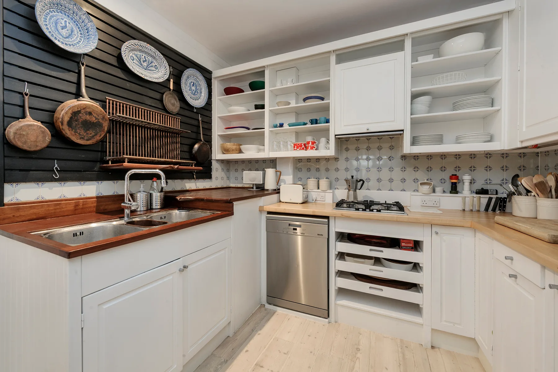 A bright kitchen with white cabinets, a sink, and a stovetop.