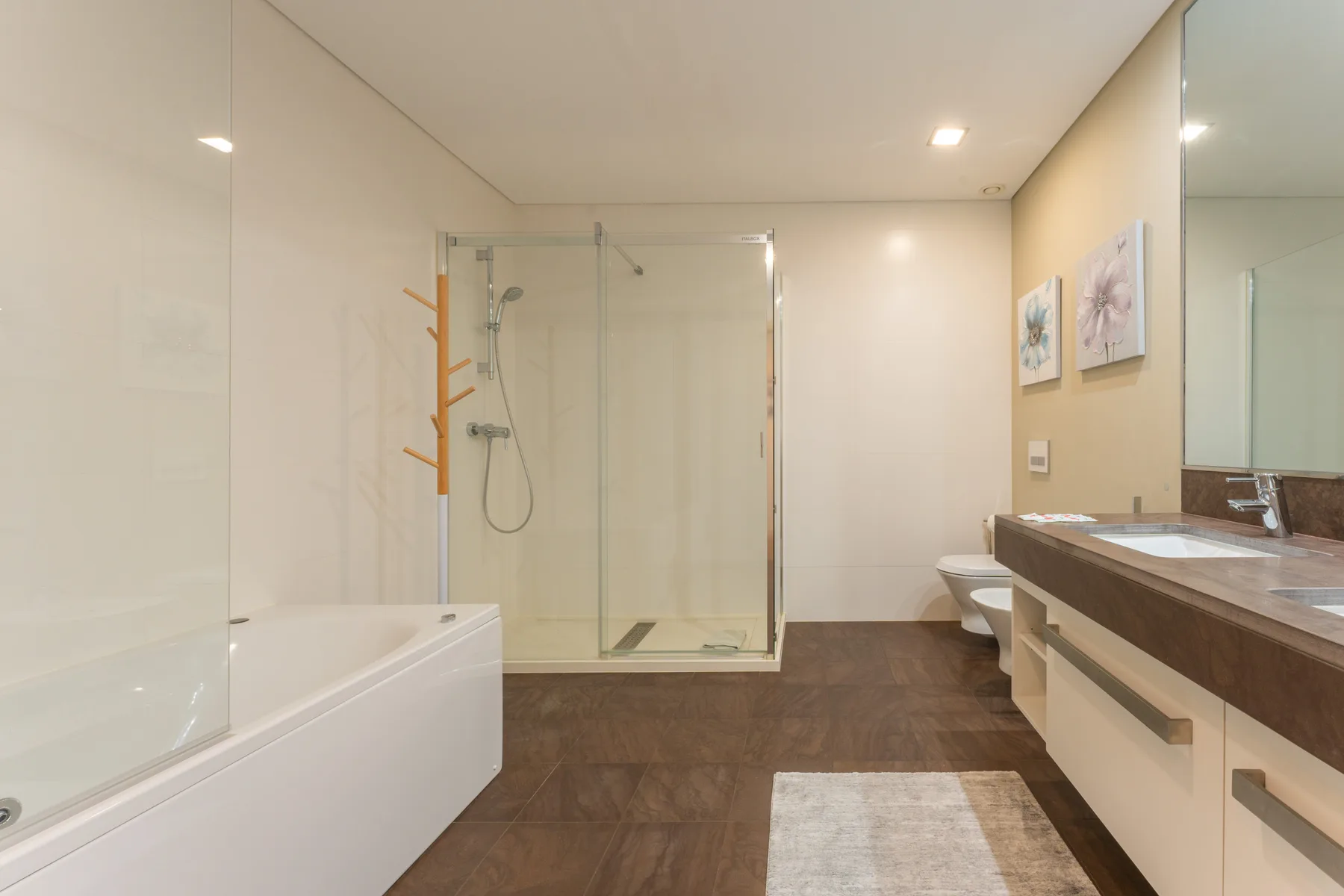 A bright bathroom with a bathtub, glass shower, and long vanity.