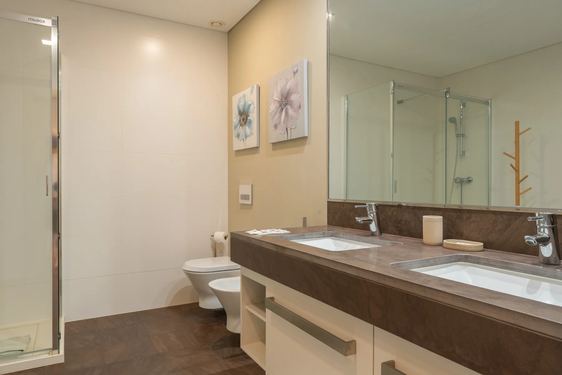 A bathroom with a long vanity, two sinks, and a glass shower.