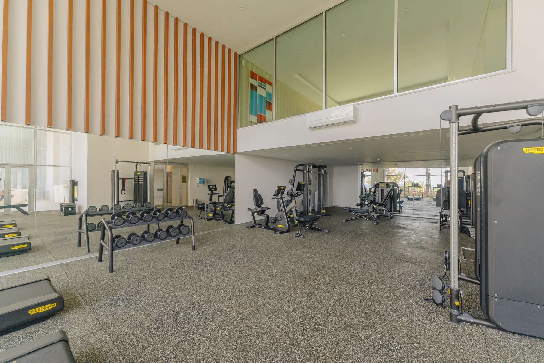 A spacious gym with exercise machines and free weights.