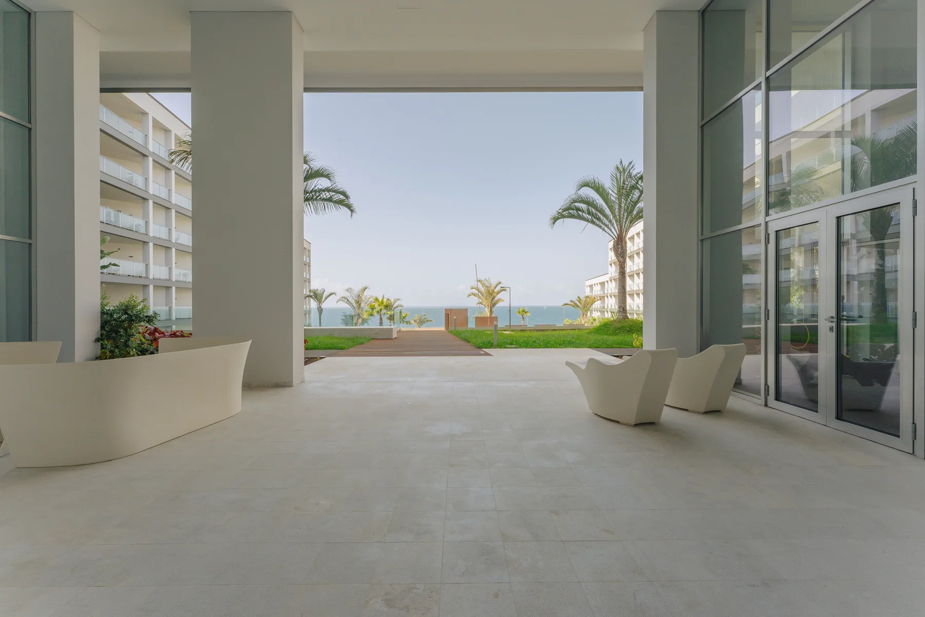 A covered outdoor lounge opens onto landscaped grounds and an ocean view.