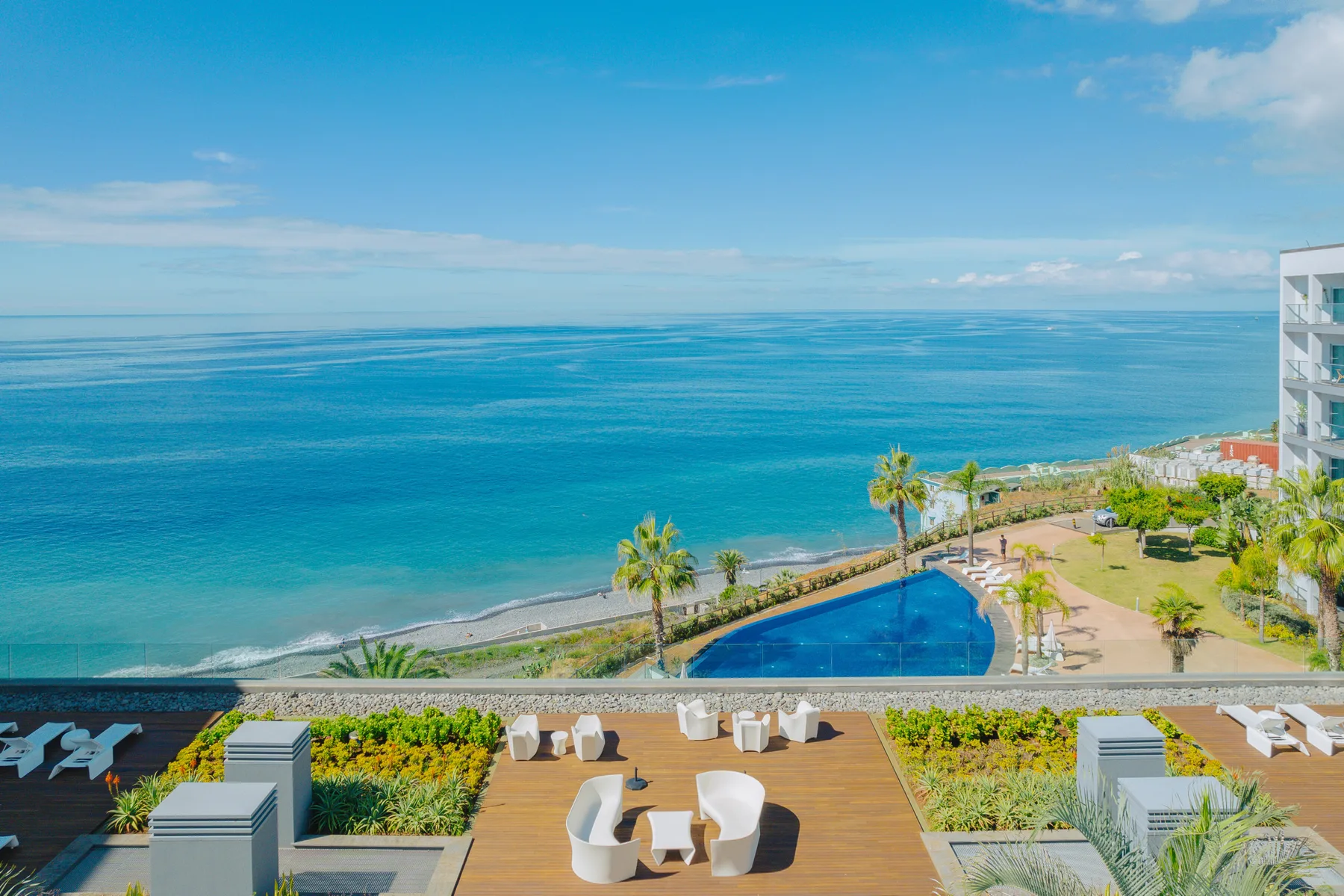 A coastal terrace overlooks a swimming pool and the ocean.