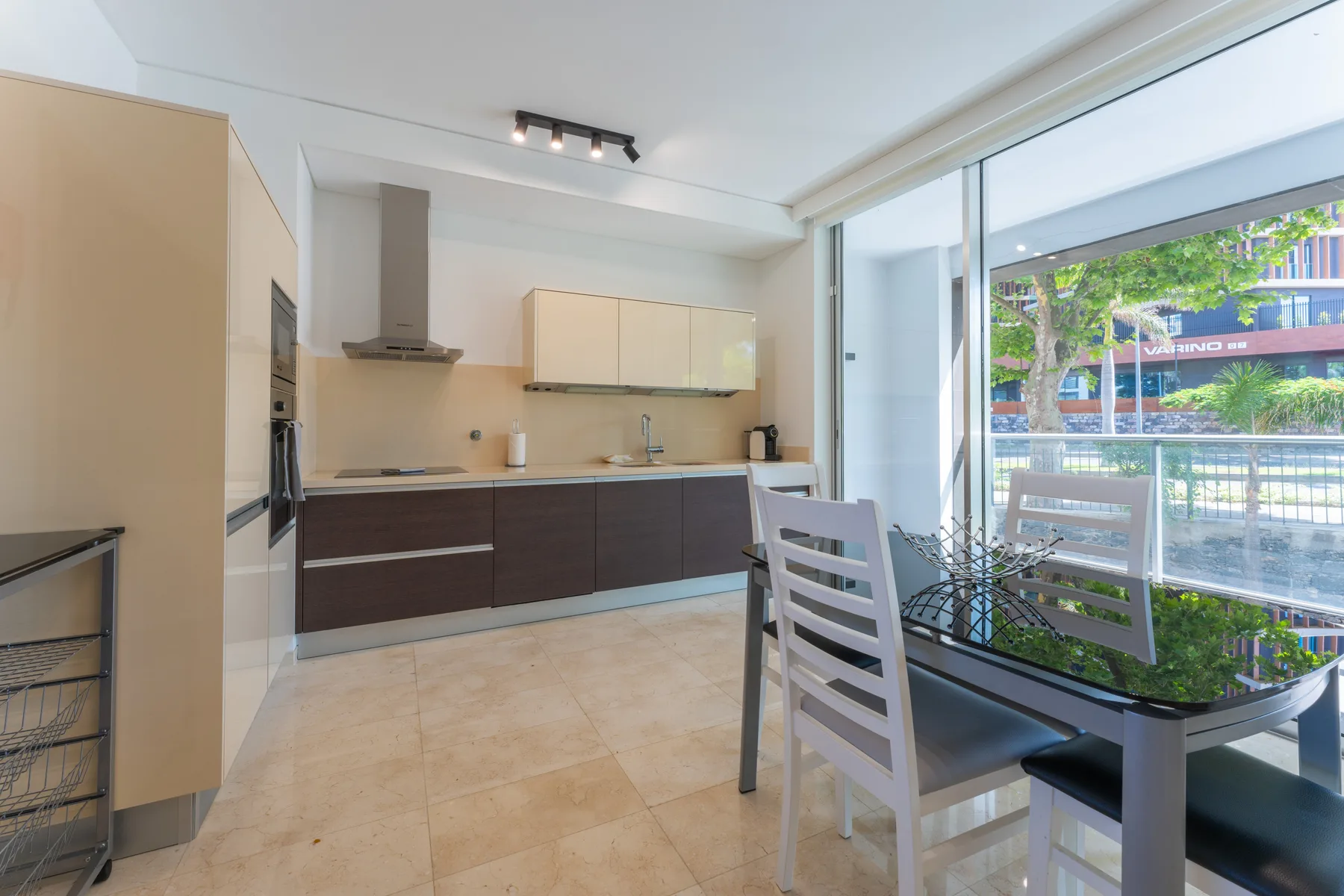 A modern kitchen and dining area opens onto a glass-enclosed balcony.