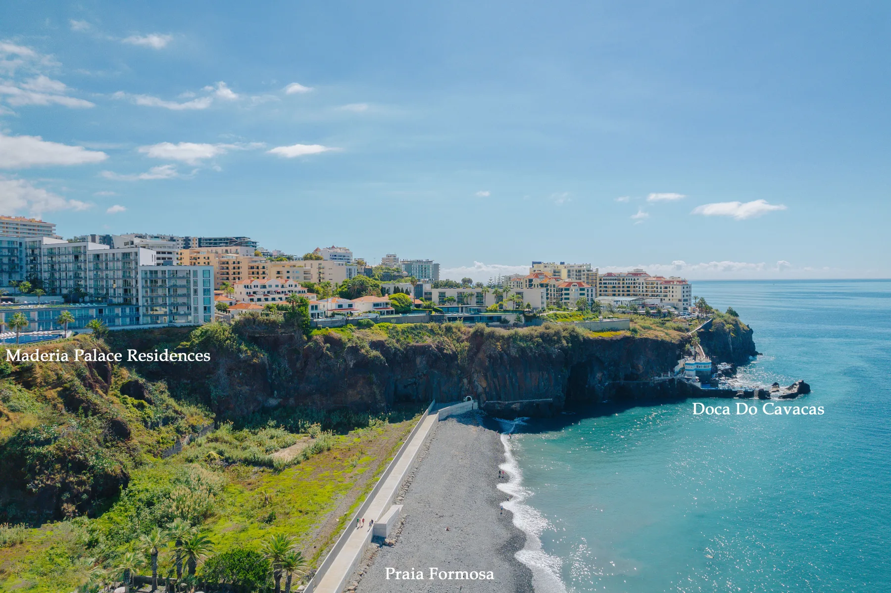 Aerial coastal view of Praia Formosa, with buildings atop the rocky shoreline.