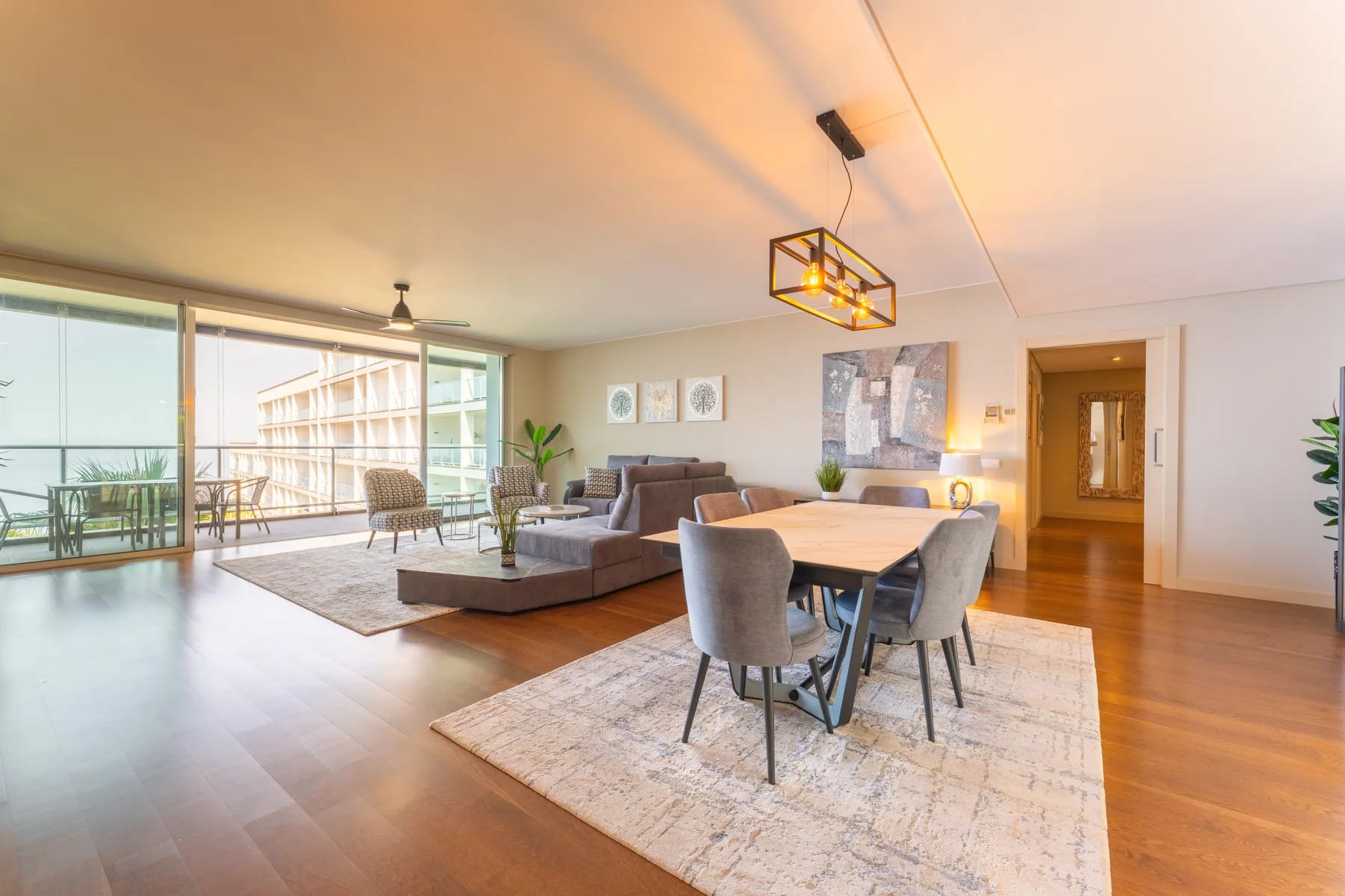 A living and dining area with seating beside large windows opening onto a balcony.
