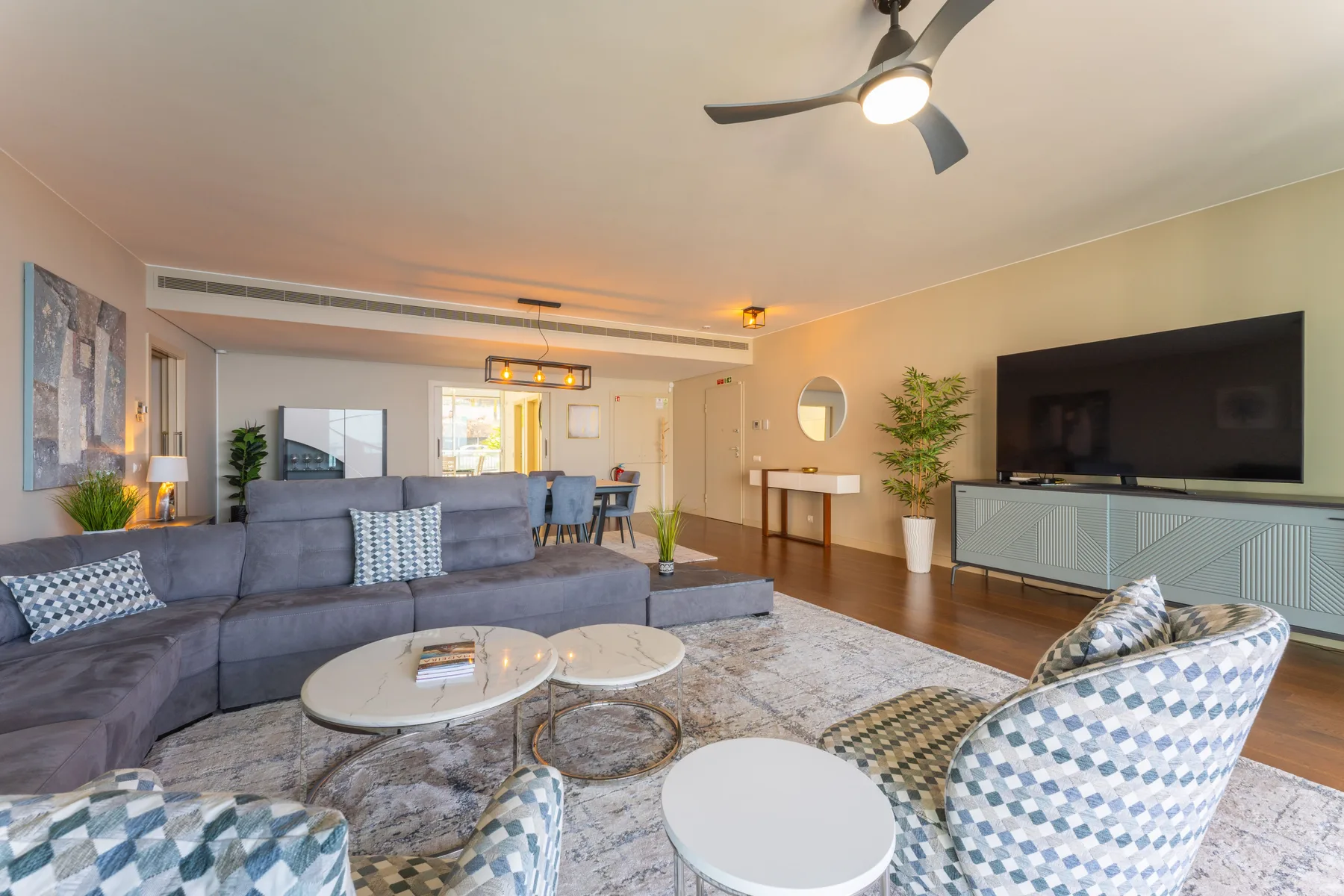 A living room with seating, a television, and a dining area.