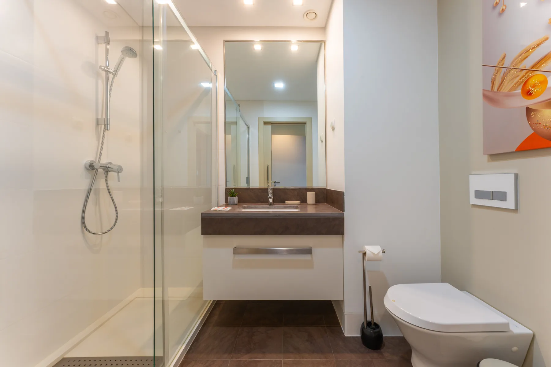 A modern bathroom with a glass shower, sink, and toilet.