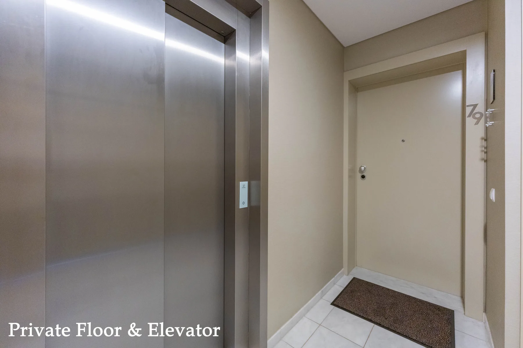 An elevator and a closed door face a tiled hallway.