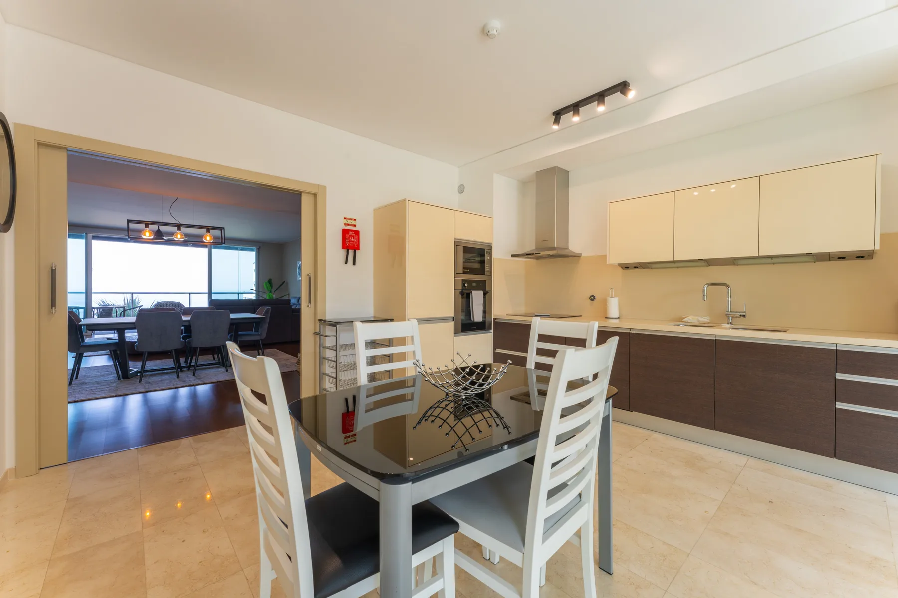 A bright kitchen and dining area with a glass table and nearby counter.