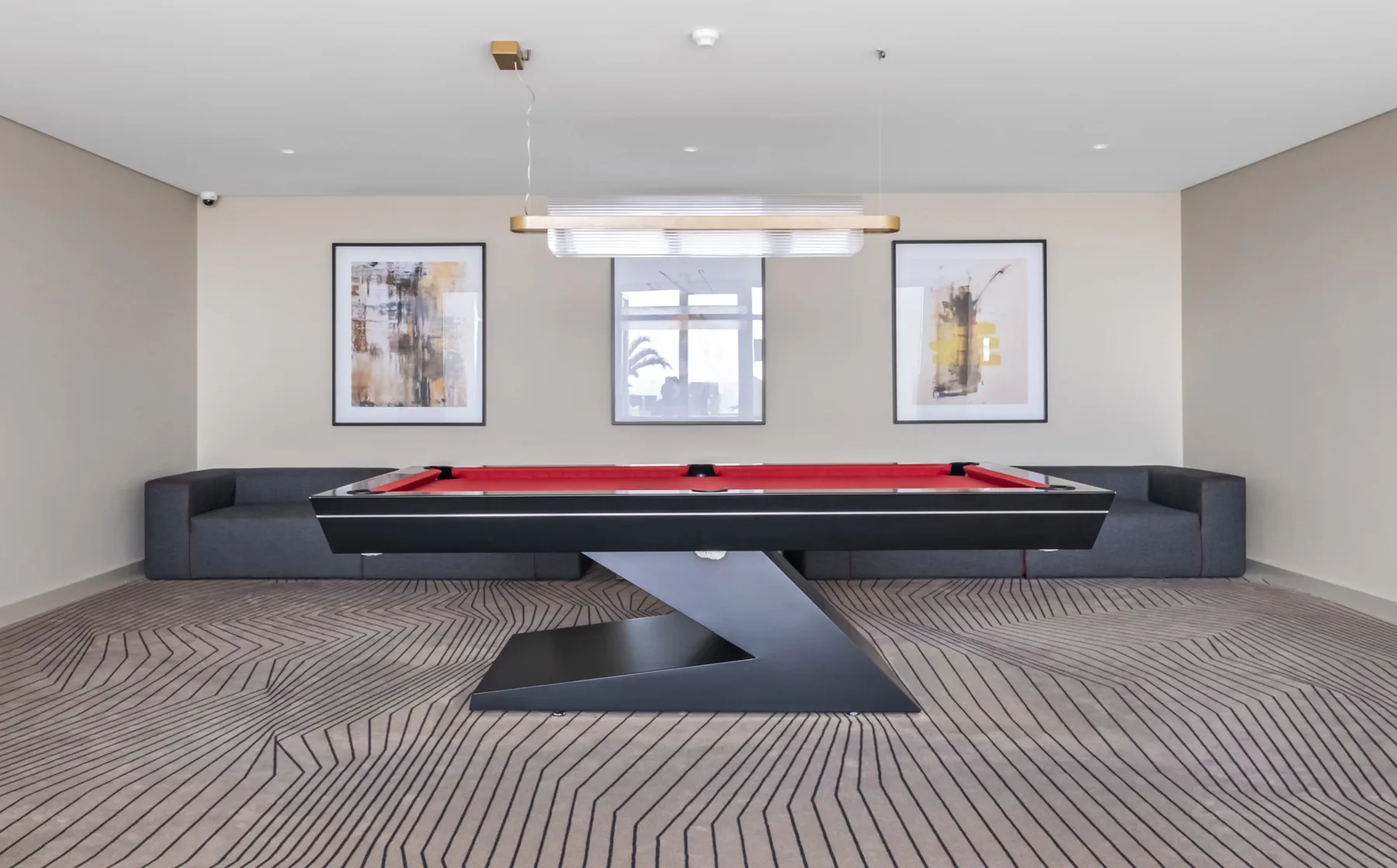 A billiards table sits in a lounge area with framed artwork on the wall.