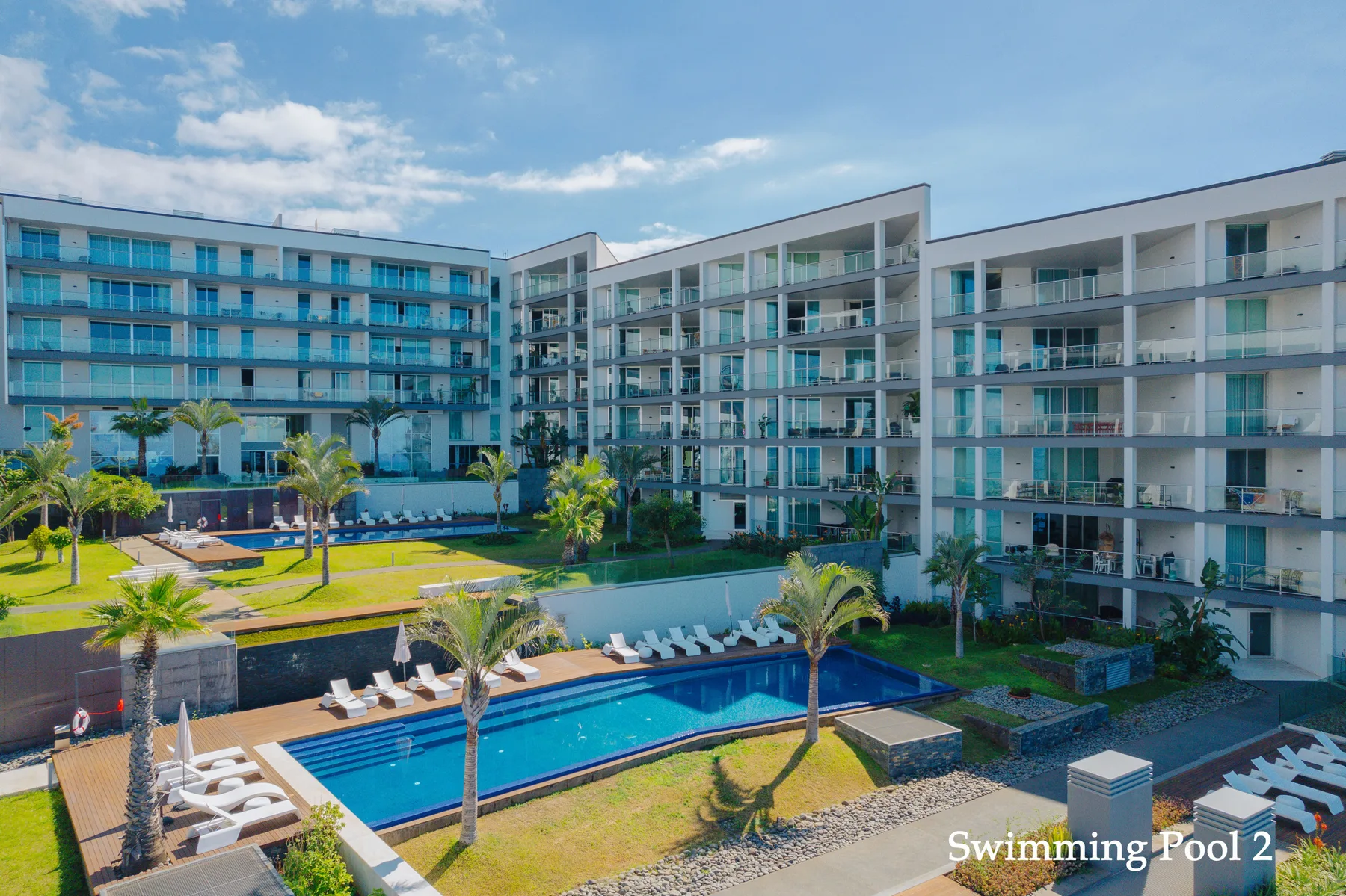 A courtyard pool sits among landscaped grounds and modern apartment buildings.