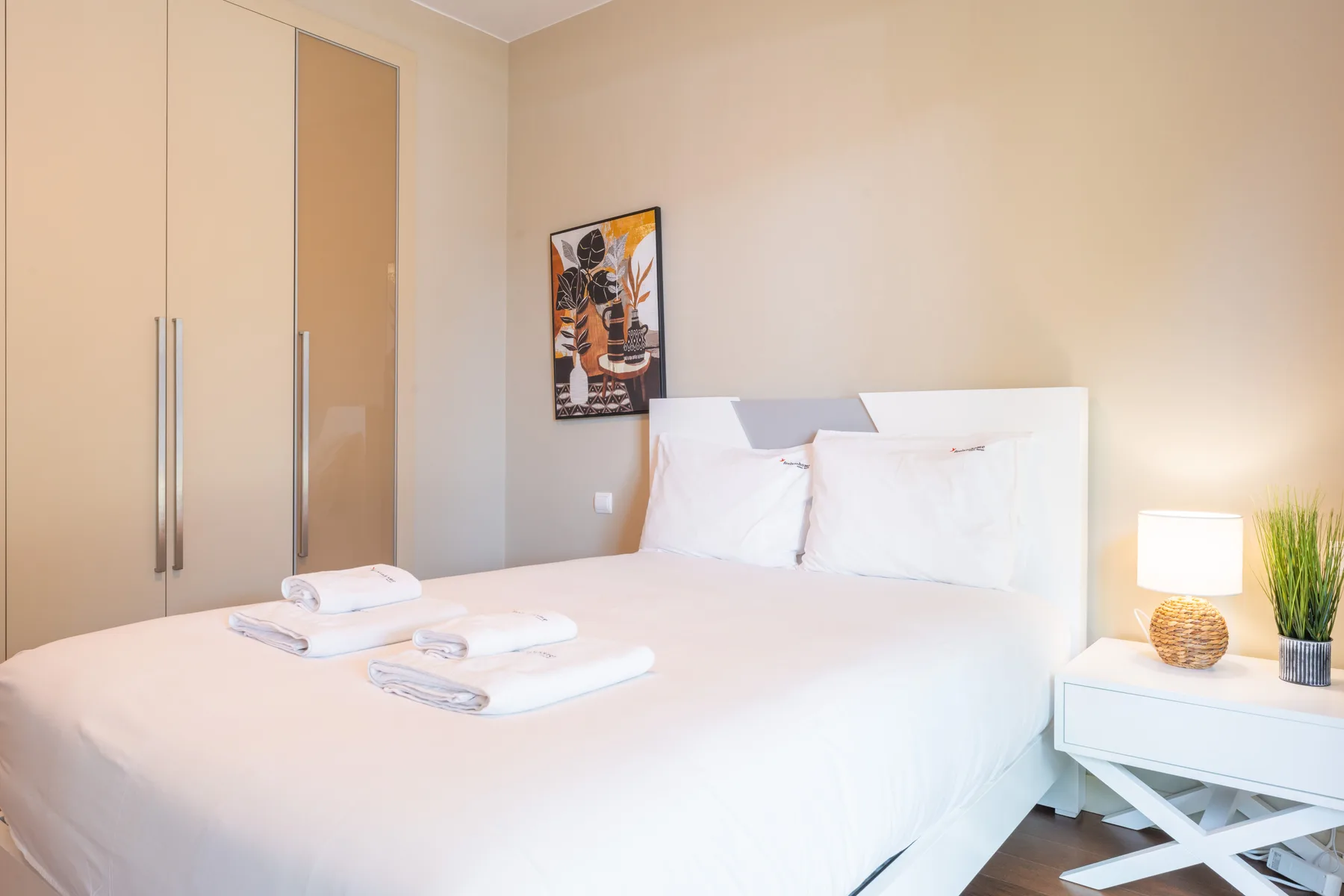 A bright bedroom with a neatly made bed and bedside table.