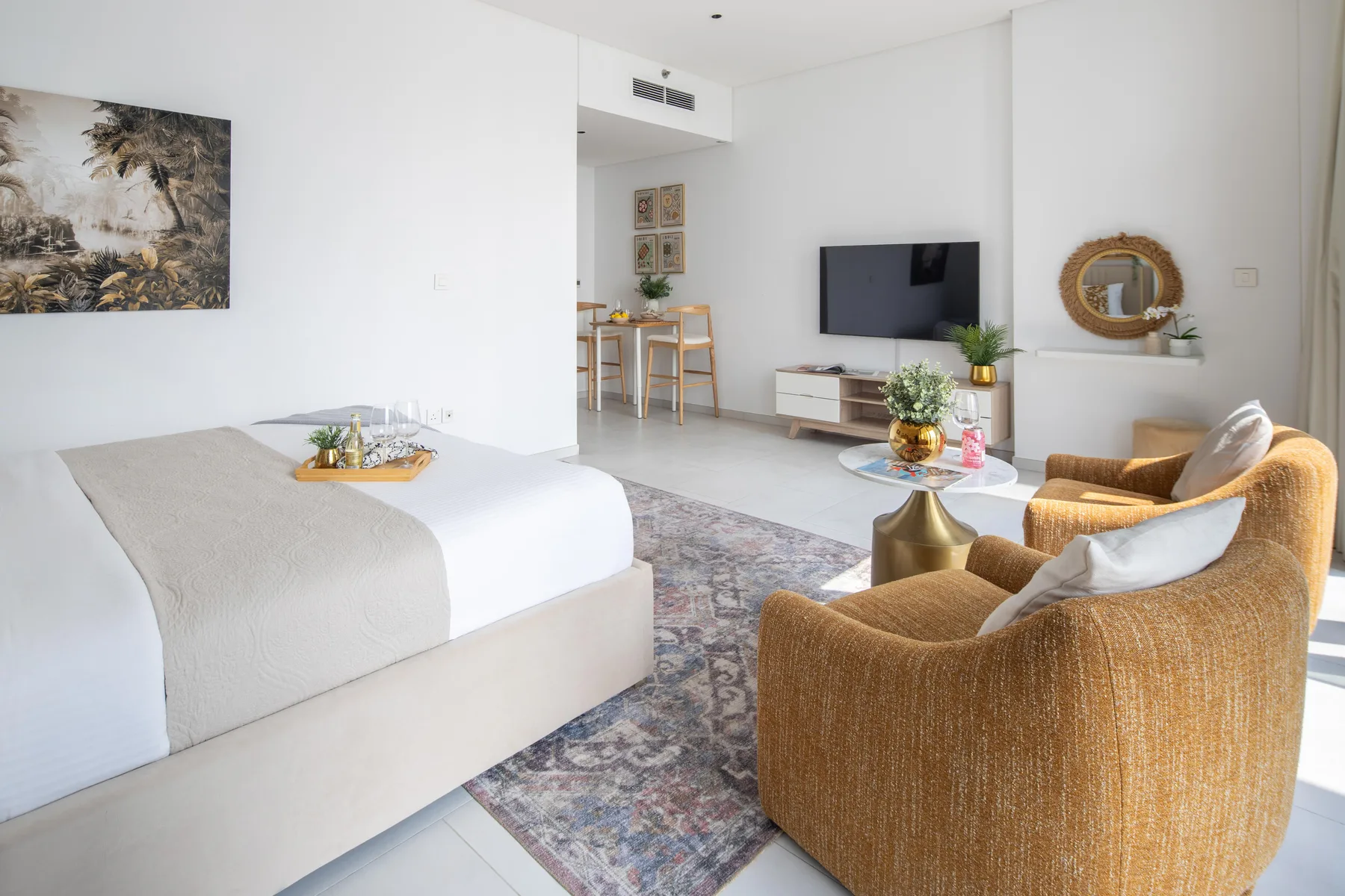 Un dormitorio luminoso con cama, televisor y zona de estar.