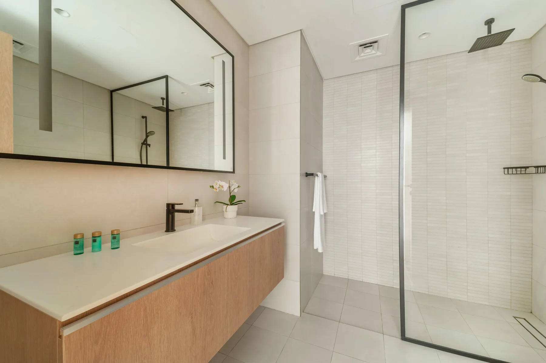 Un baño luminoso con un amplio tocador y una ducha con mampara de vidrio.