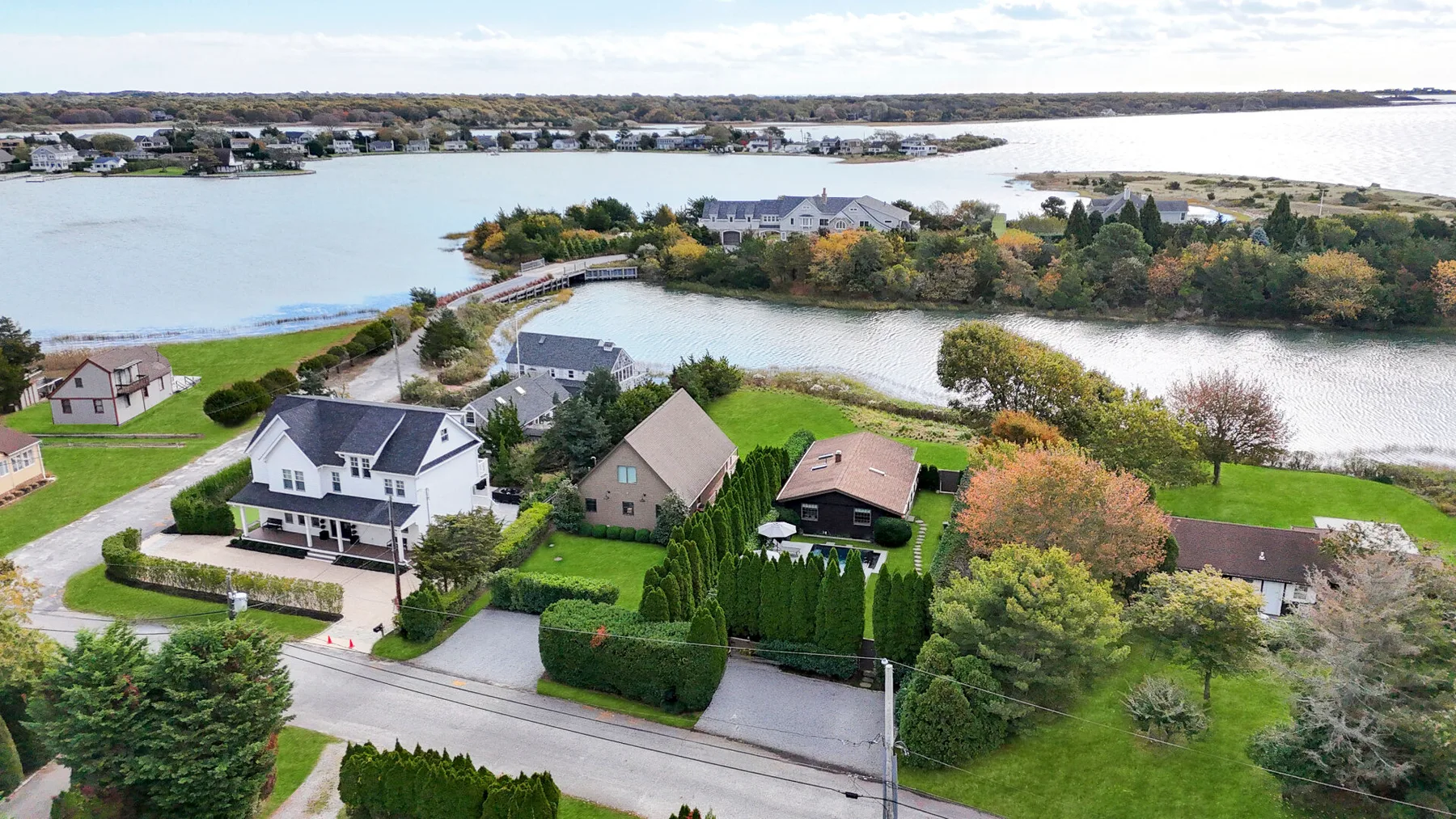 Aerial view of houses and gardens beside a coastal inlet.