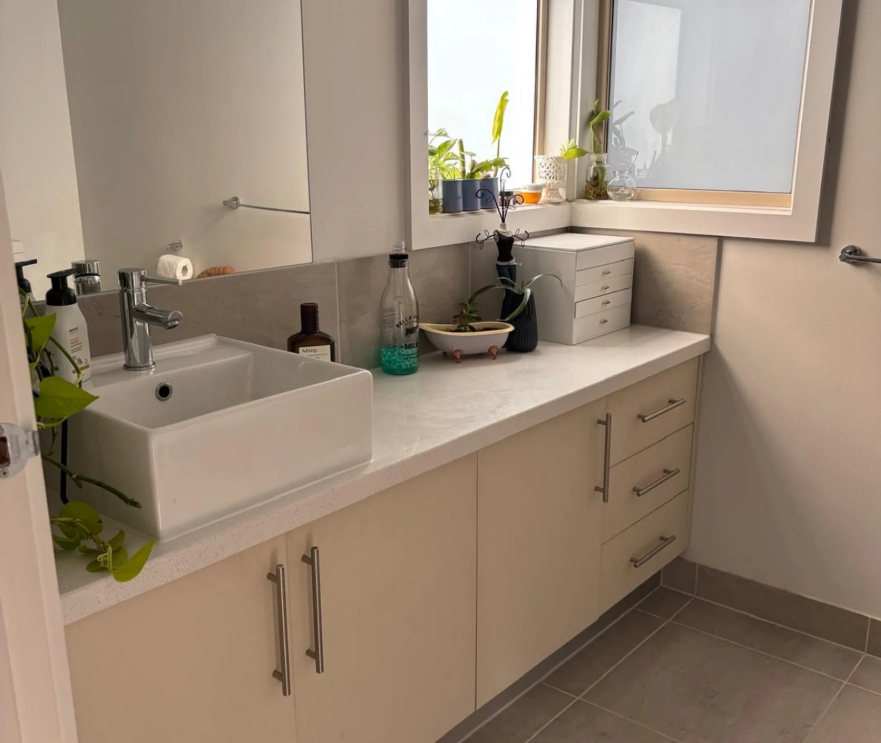 A bathroom vanity with a sink, countertop, and large mirror.