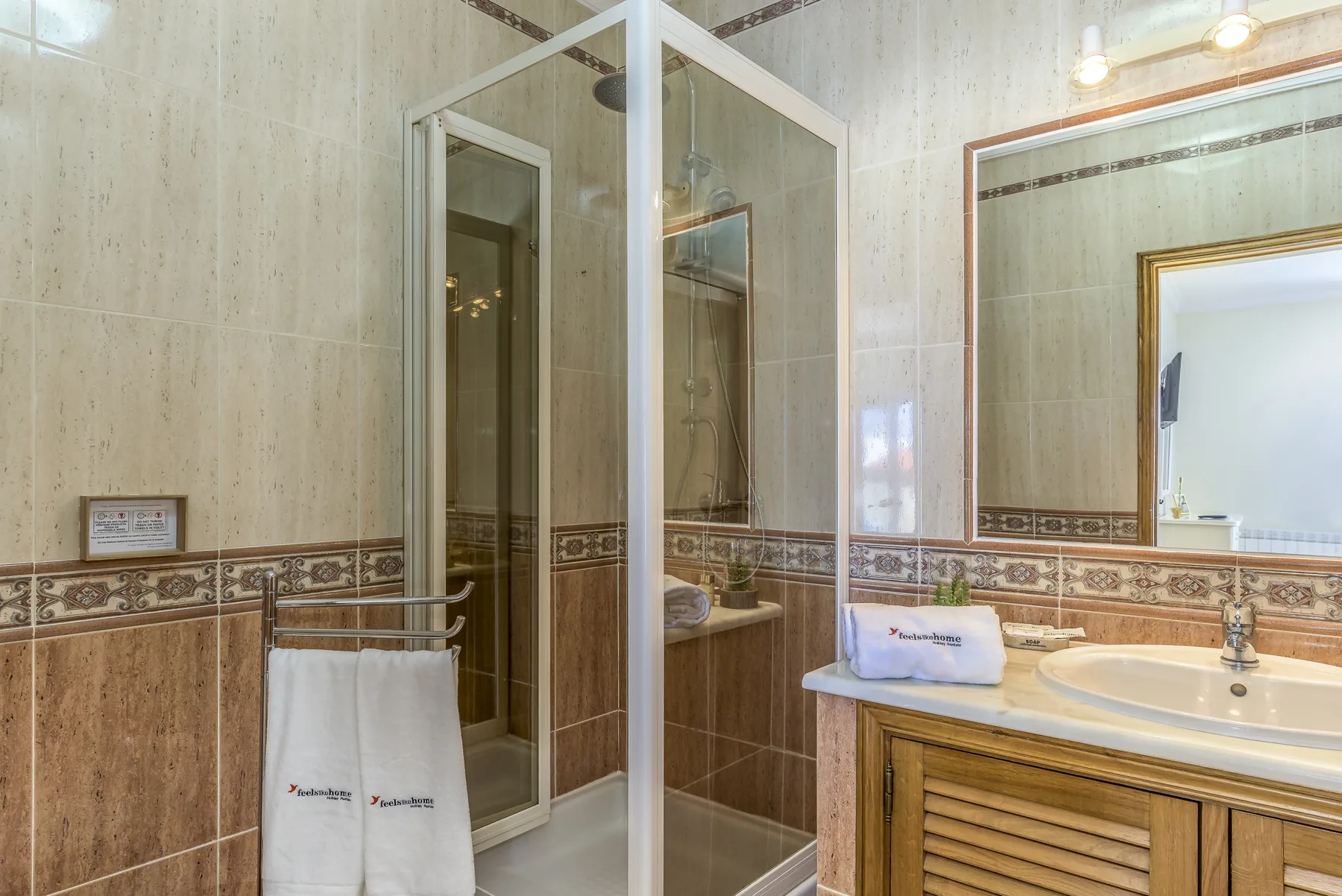 Un baño con azulejos, una ducha de vidrio y un lavabo con mueble.