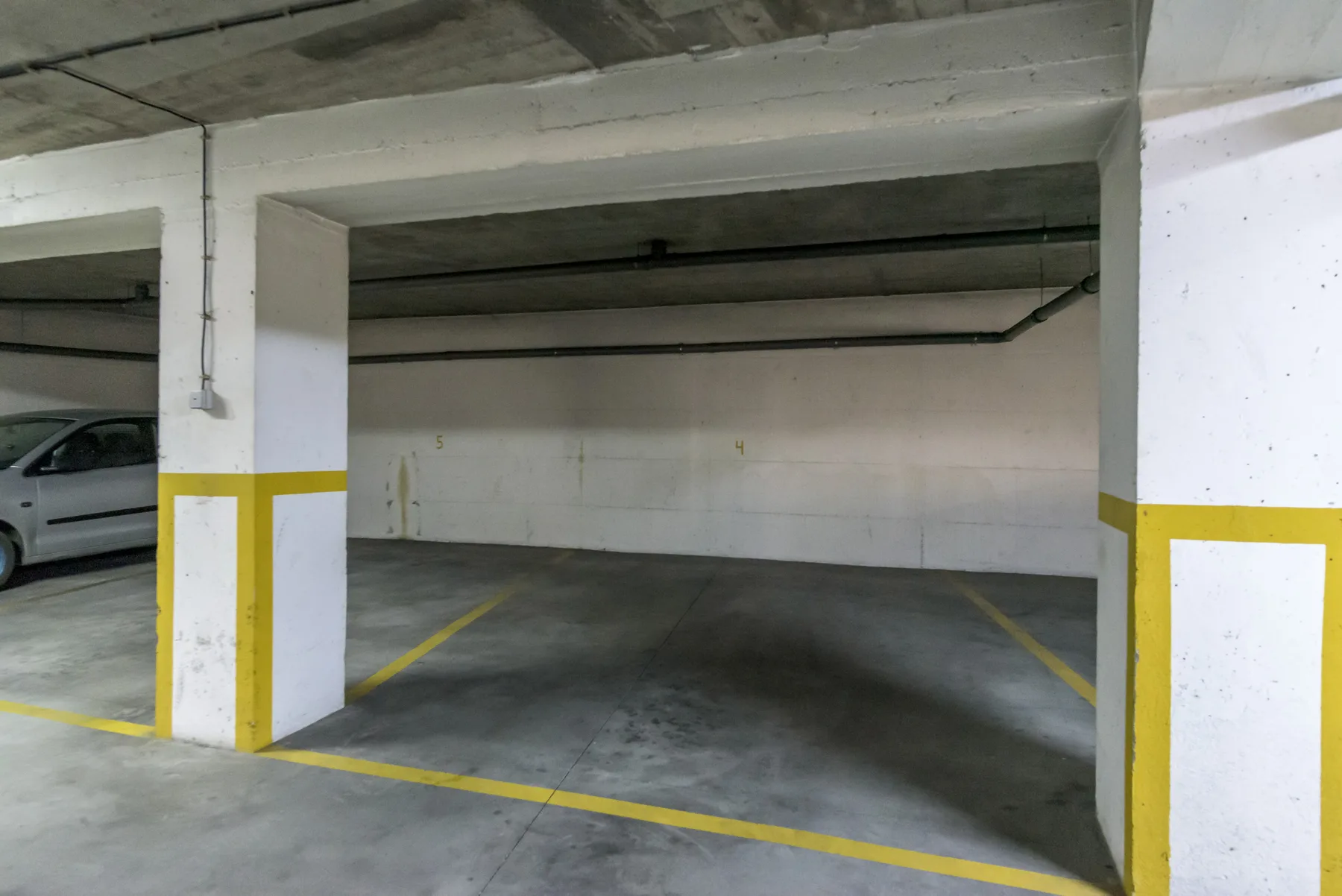 Un garaje interior con líneas amarillas que delimitan las plazas.