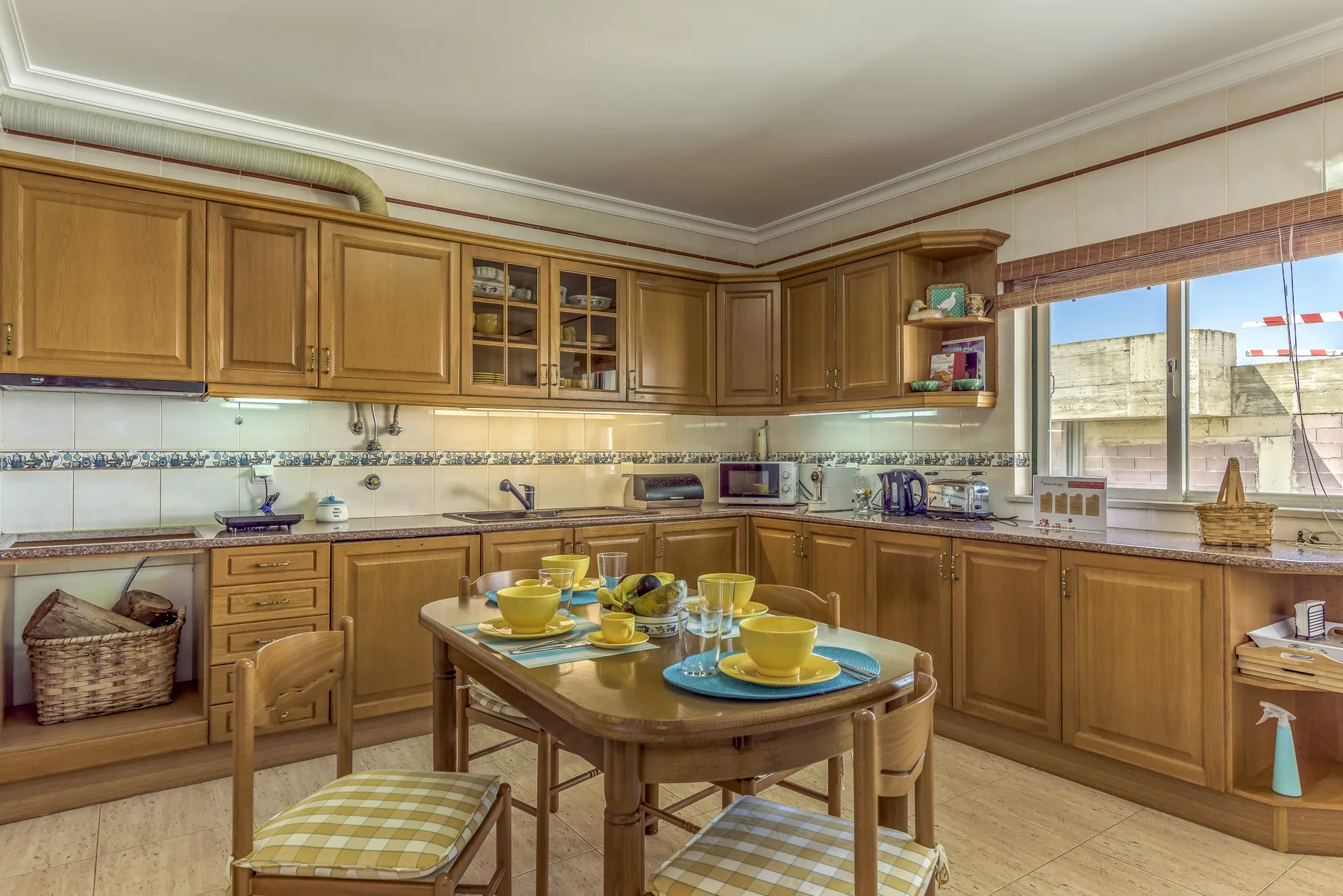 Una cocina con gabinetes de madera y una mesa de comedor con vajilla.