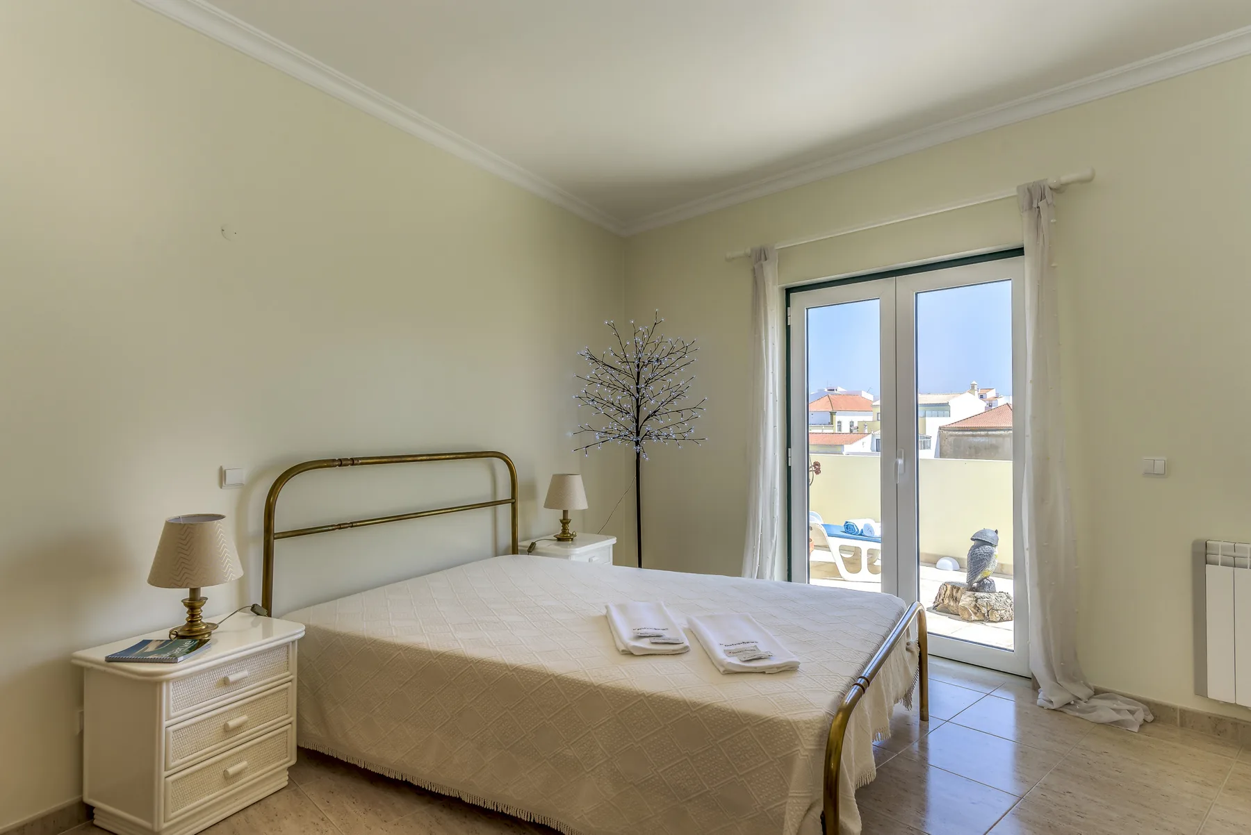 Un dormitorio con una cama bien tendida y puertas de cristal que dan a un balcón.